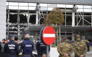 police and soldiers in front of blown out windows at Zaventem Airport